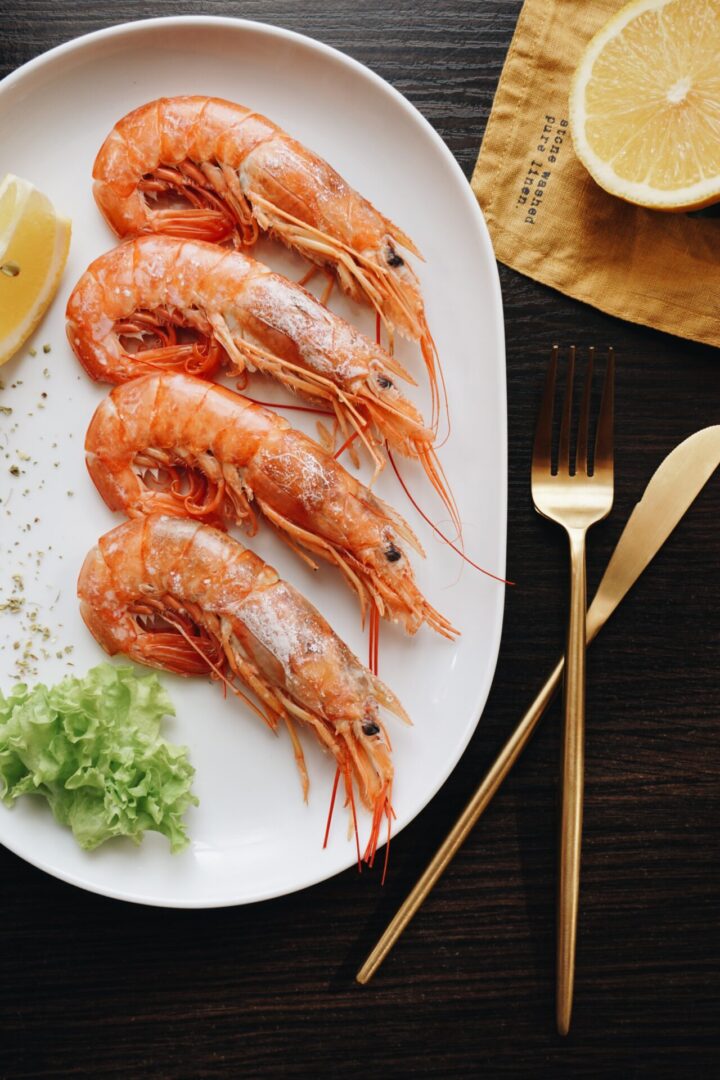 A plate of shrimp with lemon and lettuce.